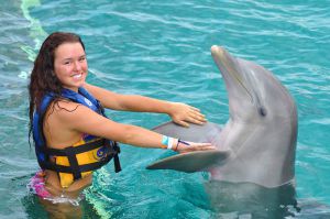 mujer joven interactuando con delfín