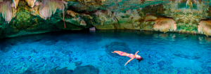 mujer joven flotando boca arriba en un cenote COVID Cancun