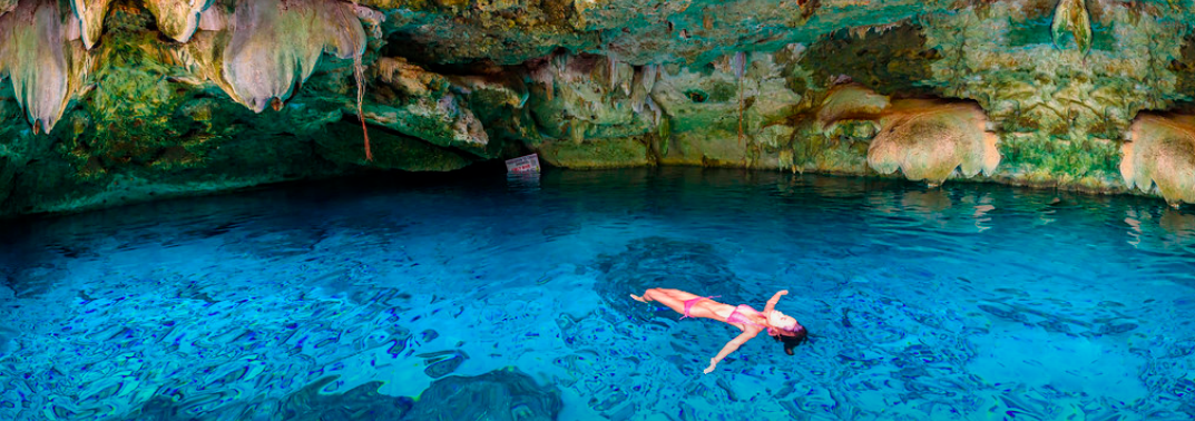 mujer joven flotando boca arriba en un cenote