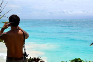 Turista tomando fotos de la hermosa vista del mar caribe en Tulum