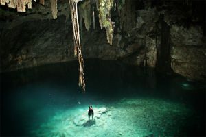 hombre joven nadando en aguas cristalinas de cenote subterraneo
