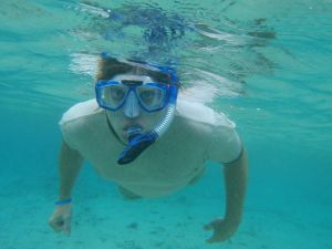 Hombre joven bajo el agua practicando snorkel