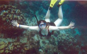 Mujer joven bajo el agua haciendo snorkel