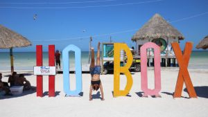 mujer parada de manos en letras de holbox