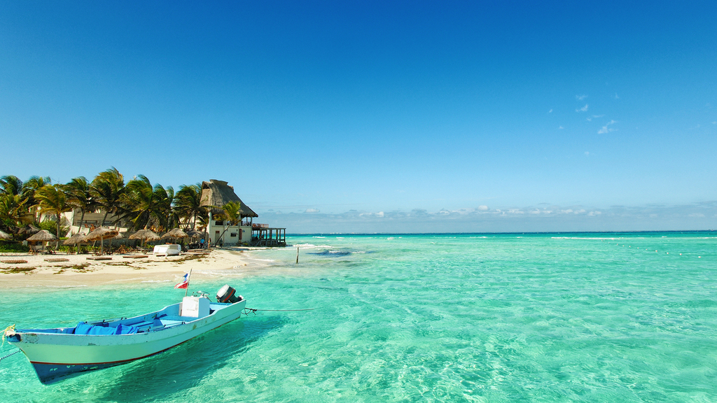 Playa de cozumel con aguas cristalinas y una lancha tipica