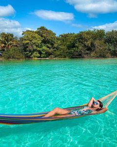 mujer joven acostada en hamaca en las aguas de bacalar